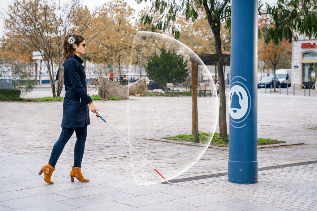 Photo d'une femme se déplaçant avec une canne blanche, et détectant un poteau grâce à Rango.